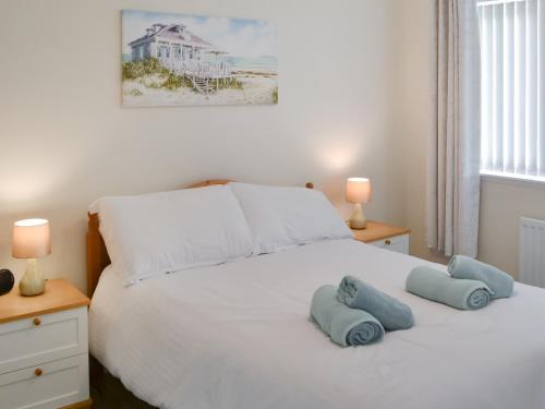 a bedroom with a white bed with two blue pillows on it at The Malt House in Rothbury