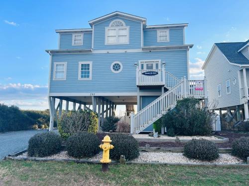 a blue house with a yellow fire hydrant in front of it at Sunny Times in Holden Beach