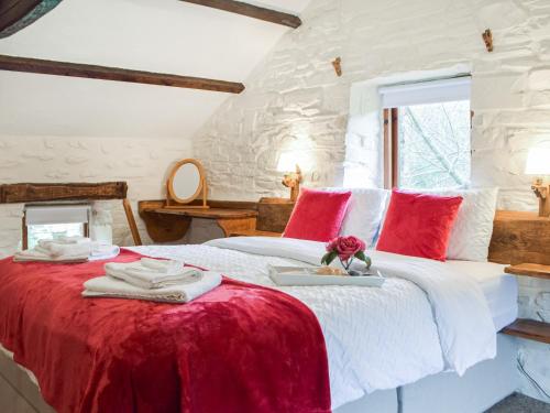a bedroom with a large white bed with red pillows at Ty Tarw - Uk46189 in Llanybyther