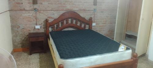 a wooden bed in a room with a brick wall at Wasi in La Falda
