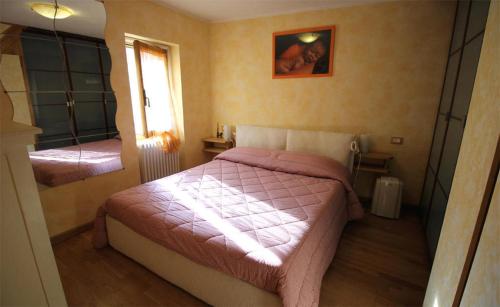 a small bedroom with a pink bed and a mirror at La Casetta Vacanze in Molini di Triora