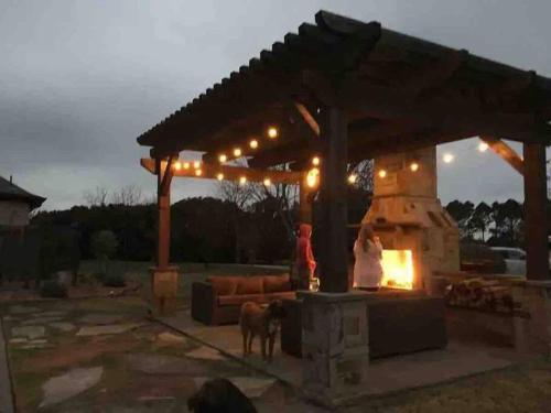 a patio with an outdoor fireplace with a couch and a dog at Beautiful Farmhouse w/ pool on 6 acres ranch in Aubrey