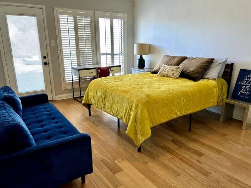 a bedroom with a bed with a yellow bedspread and a couch at Beautiful Farmhouse w/ pool on 6 acres ranch in Aubrey