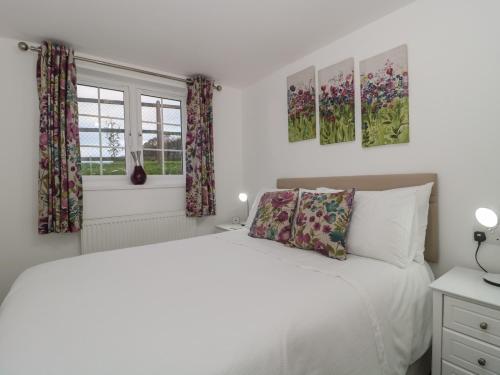 biała sypialnia z łóżkiem i 2 oknami w obiekcie Moorcrest w mieście Bideford