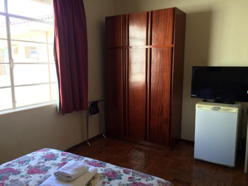 a bedroom with a dresser and a bed and a tv at Casa da Ponte Hotel in Goiás