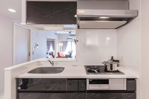 Una cocina blanca con fregadero y estufa. en FDS AURA, en Osaka