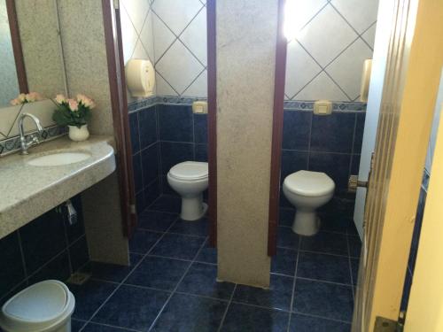 a bathroom with two toilets and two sinks at Casa da Ponte Hotel in Goiás