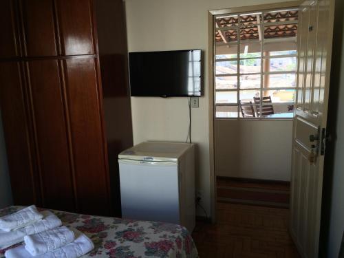a room with a bed and a television and a window at Casa da Ponte Hotel in Goiás
