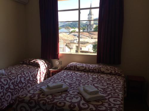 a room with two beds and a window with a view at Casa da Ponte Hotel in Goiás