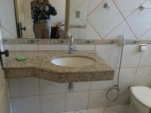 a woman taking a picture of a sink in a bathroom at Casa da Ponte Hotel in Goiás