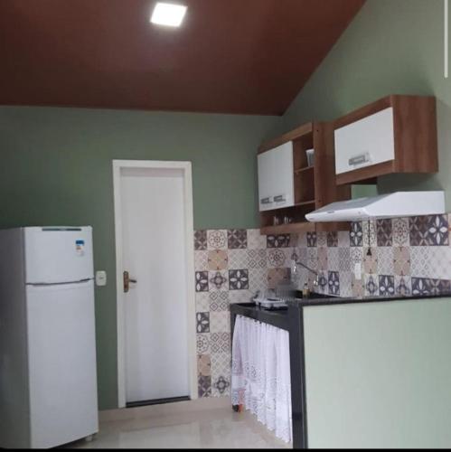uma cozinha com paredes verdes e um frigorífico branco em Casa da Pedra em Aracê