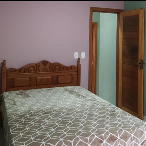 1 dormitorio con 1 cama con cabecero de madera en Casa da Pedra en Aracê