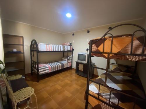 Zimmer mit 2 Etagenbetten und einem TV in der Unterkunft La casa de los Viajeros in Huarmey