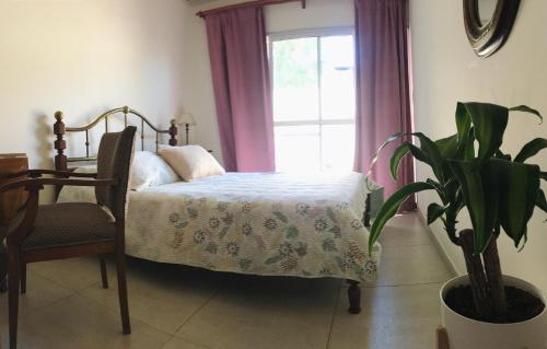 1 dormitorio con 1 cama, 1 silla y 1 ventana en Brisa en San Antonio de Areco