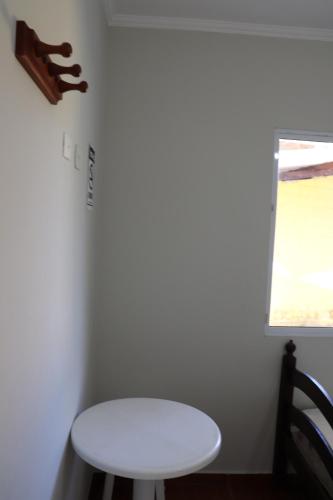 - une table blanche et un tabouret dans la chambre dans l'établissement Camping Pousada Ilha do Mel - Frente ao Mar, à Boraceia