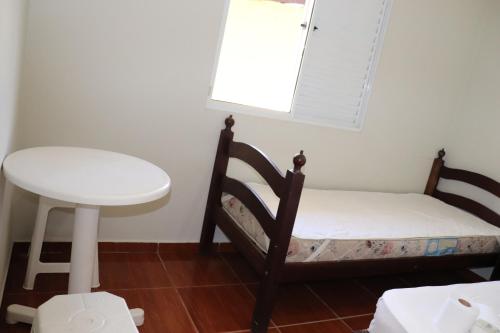 een kleine kamer met een bed, een tafel en een raam bij Camping Pousada Ilha do Mel - Frente ao Mar in Boracéia