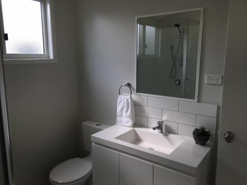 a white bathroom with a toilet and a sink at Longreach Private Apartments in Longreach