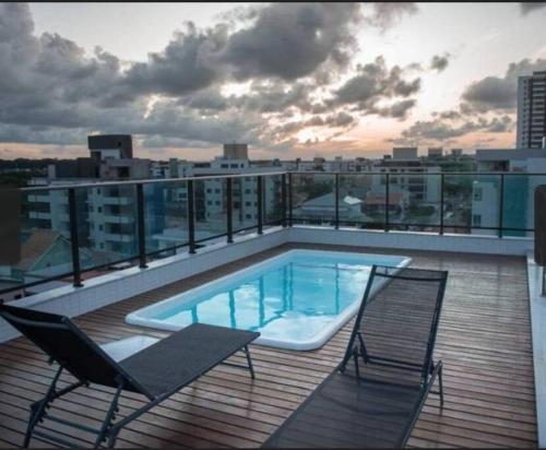 a deck with a swimming pool and two chairs on a building at Flat com piscina a 200m da praia in Cabedelo
