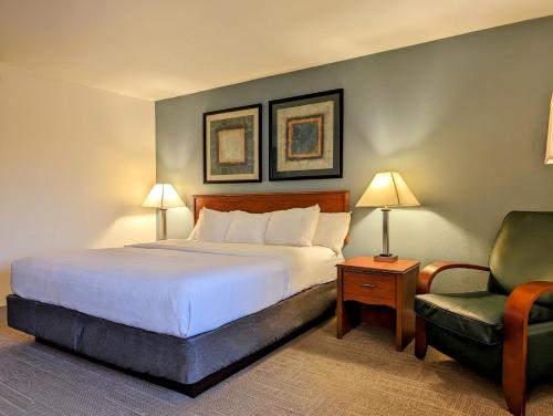 a hotel room with a bed and a chair at La Quinta Inn by Wyndham Chicago Willowbrook in Willowbrook