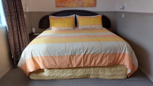 a bed with orange and yellow pillows in a bedroom at Bed and Breakfast Happy Home Taupo Accommodation in Taupo