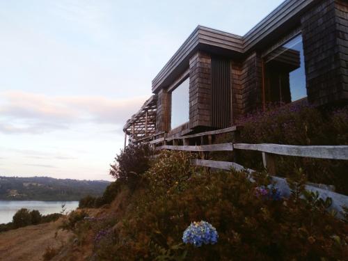 a house on the side of a hill with flowers at CABAÑA LA RECALADA in Castro