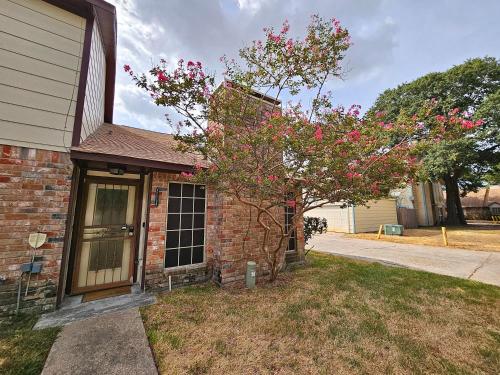 a brick house with a tree with pink flowers at Spacious 2 Bedroom Townhome/ /15 min from downtown in Houston