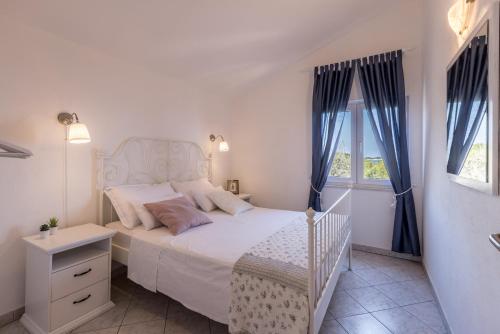een slaapkamer met een wit bed en een raam bij Apartments by the sea Milna, Vis - 8946 in Rukavac
