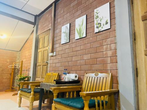 een eetkamer met 2 houten stoelen en een bakstenen muur bij Khaosok Monkeys & River Camps in Khao Sok