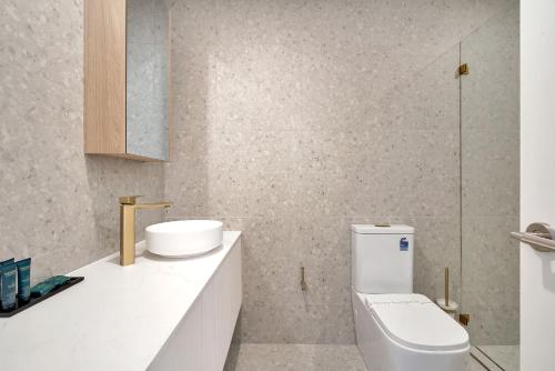 a white bathroom with a toilet and a sink at Blanca Beach House 2 Vincentia in Vincentia