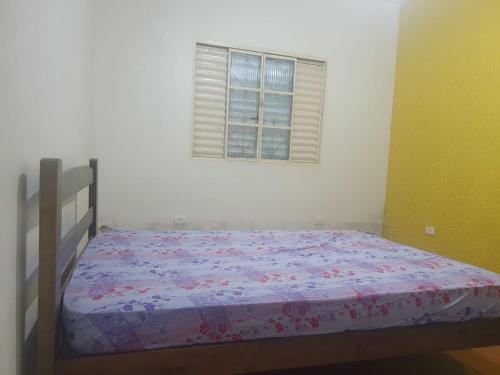 ein Bett in einem Schlafzimmer mit Fenster in der Unterkunft Casa de Temporada Próximo a Praia in Caraguatatuba