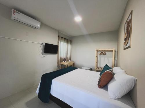 a bedroom with a white bed and a tv at Sam Day Suites in Natal