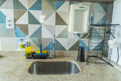 a kitchen sink with a soap dispenser on a wall at Apartamento privativo Pindamonhangaba-SP in Pindamonhangaba