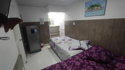 Habitación pequeña con cama y nevera pequeña. en Jackson House Inn en San Andrés