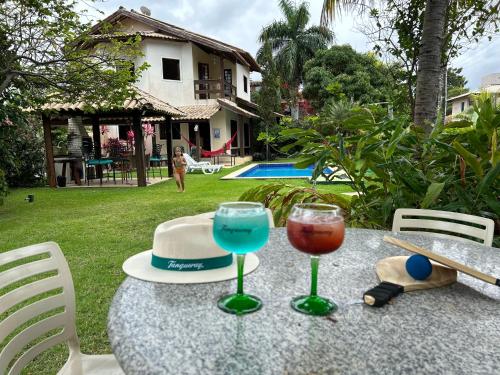 uma mesa com dois copos de vinho e um chapéu em Casa Bege - Gaia aluguel temporada Mcz em Maceió