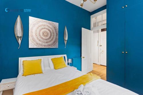 ein blaues Schlafzimmer mit einem Bett mit gelben Kissen in der Unterkunft Tranquil 2 bed apartment Edinburgh in Edinburgh