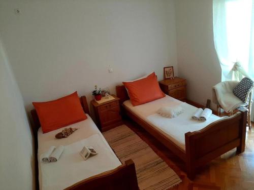 2 letti in una piccola camera con cuscini arancioni di Apartments by the sea Duce, Omis - 21876 a Omiš (Almissa)