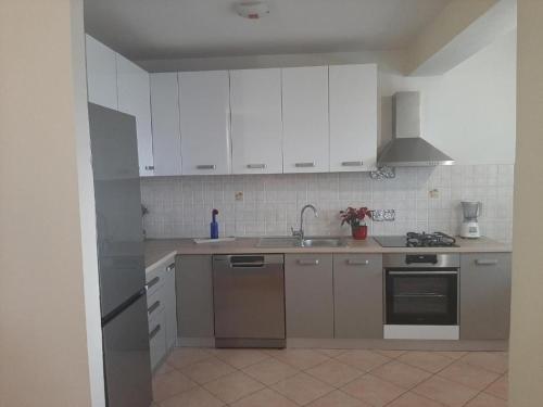 una cucina con armadi bianchi e lavandino di Apartments by the sea Duce, Omis - 21876 a Omiš (Almissa)