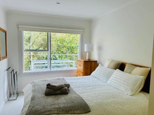 a white bedroom with a large bed with a window at Sandy Bay Haven in Sandy Bay