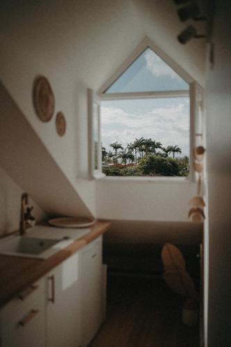a kitchen with a window with a view of palm trees at Ti Studio Bohème, avec citerne in Le Gosier