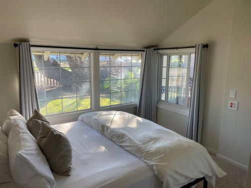 a bed in a room with two large windows at Den Street Cottage in Los Alamos