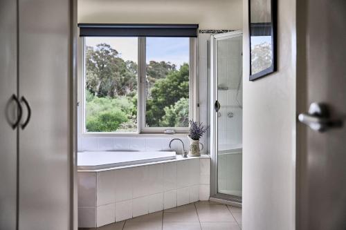 a bathroom with a bath tub and a window at Boatshed Villa Green Door in Daylesford