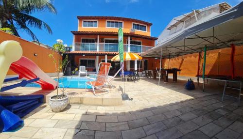 a house with a pool with a slide and a playground at Pousada paraiso das conchas hostel in Cabo Frio