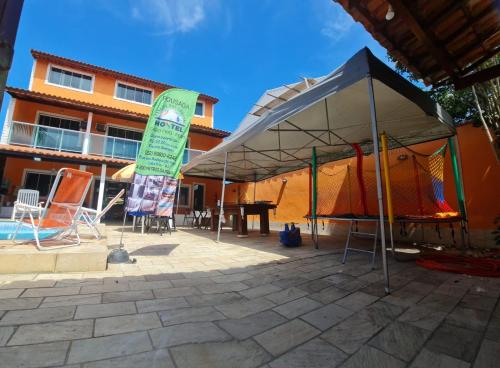 a tent with a table and chairs next to a building at Pousada paraiso das conchas hostel in Cabo Frio