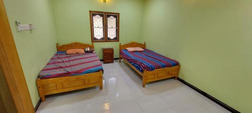 twee bedden in een kleine kamer met een raam bij Karainagar Holiday Home 
