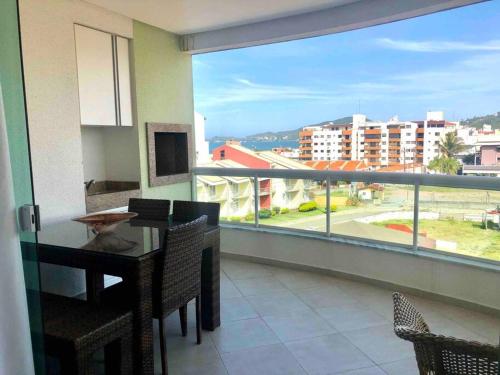 a dining room with a table and a large window at Muito confortável, vista do mar, todo climatizado in Bombinhas