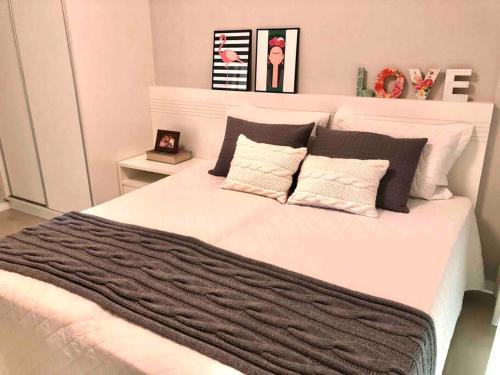 1 dormitorio con 1 cama blanca grande con almohadas blancas y negras en Muito confortável, vista do mar, todo climatizado en Bombinhas