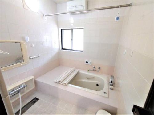 a white bathroom with a tub and a window at 奈良公園から車で約12分のお宿 