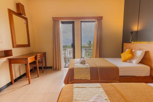 a hotel room with two beds and a desk and a window at Hotel Griya Katarina in Ambarawa
