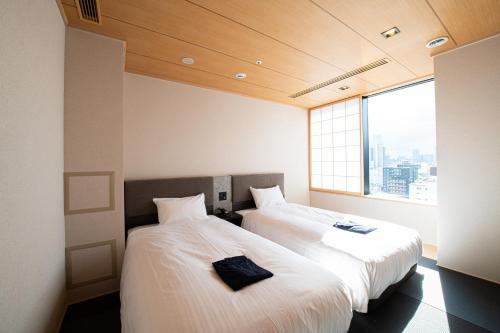 大阪的住宿－Welina Hotel Premier Osaka Namba，带窗户的客房内的两张床