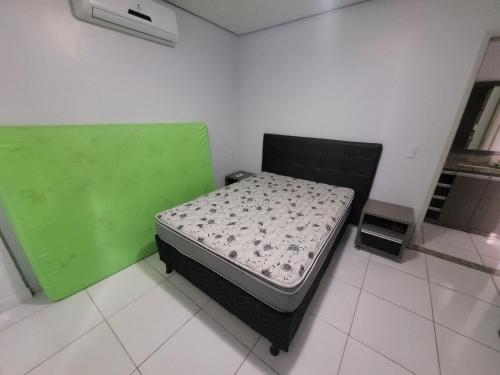 um pequeno quarto com uma cama verde e branca em Lagoa Flat Service RM Hopsedagem em Caldas Novas
